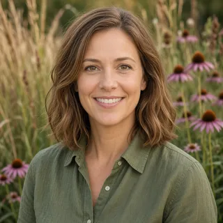 Amanda Kupsti smiling outdoors in a garden of prairie grasses and purple coneflowers